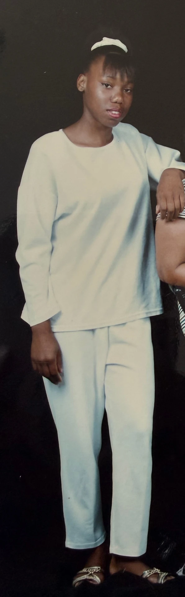 LaKeysha as a teenager, standing in a pale sweatsuit against a dark studio backdrop